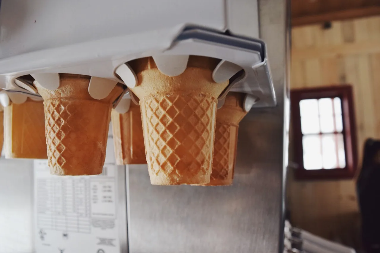 Des cornets gaufrés vides suspendus au distributeur, au-dessus de la machine à molle.